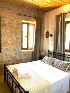 ein Schlafzimmer mit einem Bett und zwei Fenstern in der Unterkunft Pool House ( Πέτρινο σπίτι με πισίνα ) in Itylo