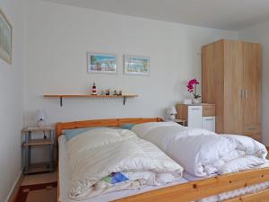 a bedroom with a wooden bed with white sheets at Gemütlicher Bungalow in Freest in Freest