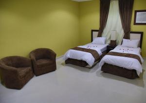 sypialnia z 2 łóżkami i krzesłem w obiekcie أندلسية الوسام w mieście Taif
