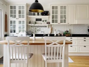 uma cozinha com armários brancos e uma mesa e cadeiras em Holiday home SPÅNGA em Estocolmo