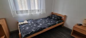 een klein bed in een kamer met een raam bij MILOJEVIĆ APARTMANI in Bečej