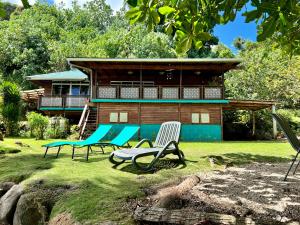 a house with two lawn chairs and a building at Fare Hotu Villa plus voiture-car in Fitii