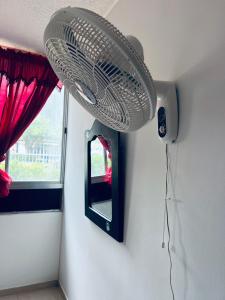 ein weißer Ventilator hängt an einer Wand neben einem Spiegel in der Unterkunft ESTANCIA MINIMA 3 NOCHES APARTAMENTO 3 HABITACIONES - 5 PERSONAS no aire acondicionado in Valledupar