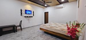 a bedroom with a bed and a desk and a tv at The Riverland Farm in Karjat