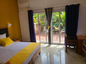 een slaapkamer met een bed en een grote glazen schuifdeur bij Hotel Les Cygnes in Antananarivo