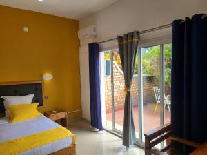 een slaapkamer met een bed en een glazen schuifdeur bij Hotel Les Cygnes in Antananarivo