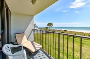 a balcony with a chair and a view of the beach at 0204 Seaside Sanctuary by Atlantic Towers in Carolina Beach +15 photos