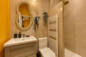 a bathroom with a sink and a toilet and a mirror at Deluxe SPA suite caramel sweetness in Melun