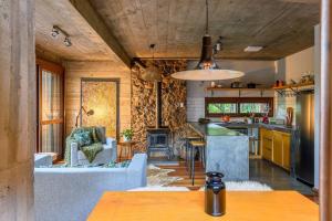 eine Küche und ein Wohnzimmer mit einer Couch und einem Tisch in der Unterkunft Casa de Piedra - Pousada NaCarapina in São Francisco de Paula