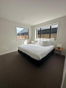 um quarto branco com uma cama grande e 2 janelas em Mountain View Escape em Frankton