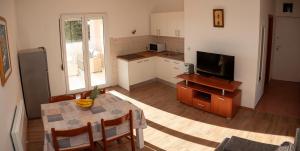 a living room with a table and a kitchen with a television at Apartment BOSS in Novalja