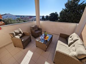 a patio with a couch and chairs on a balcony at Apartment BOSS in Novalja