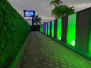 einen Zaun mit grüner Beleuchtung auf einem Gehweg in der Unterkunft Motel Prestige Pinda in Pindamonhangaba