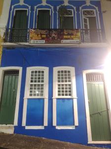 a blue building with white windows and green doors at Hostel Ateliê Laroyê in Salvador