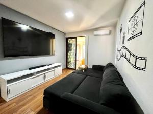 sala de estar con sofá negro y TV de pantalla plana en Casa Cactus, en Hacienda Blanca