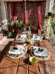 a wooden table with plates and wine glasses on it at Adella's Blue Mountain Coffee Farmstay in Kingston