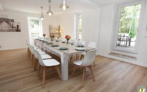 un comedor con una mesa larga y sillas blancas en Le Moulin du Béal, en Aubres