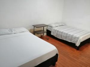 2 Betten in einem Zimmer mit einem Tisch dazwischen in der Unterkunft Hotel El Carretero in Popayan