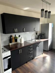 a kitchen with black cabinets and a stainless steel refrigerator at Apartament przy Browarze in Olsztyn