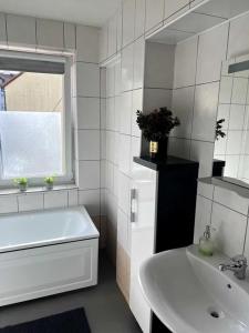 baño blanco con lavabo, bañera y ventana en Apartament przy Browarze, en Olsztyn