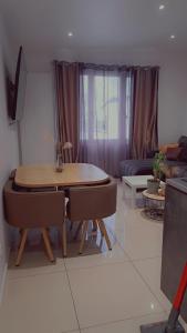 a living room with a table and chairs and a couch at DOGA Bel appartement 1er étage 4 personnes bebe in Reims