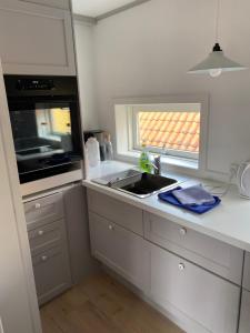 a white kitchen with a sink and a window at Skagen Bo Godt Kirkevej in Skagen