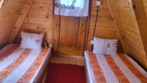 2 Betten in einem Zimmer mit Holzwänden in der Unterkunft ETNO SELO VEZIROV RANČ in Sjenica