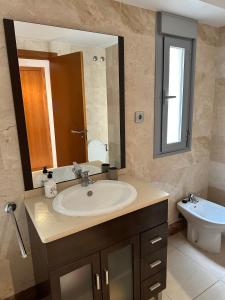 a bathroom with a sink and a mirror and a toilet at Vive Vera Rentals - Puerto Rey Apto Marina 2Habs in Los Amarguillos