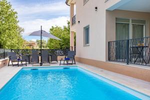 a swimming pool with chairs and an umbrella on a balcony at Villa IN in Nova Vas