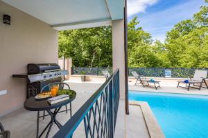 a patio with a table and a grill and a pool at Villa IN in Nova Vas