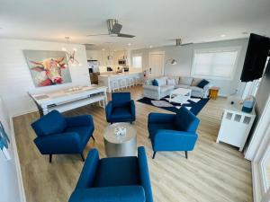 een grote woonkamer met blauwe stoelen en een bank bij Saltmeadow House in Surf City