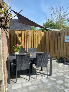a patio with a table and chairs and a fence at gezellige cottage in zeeland in Sint Annaland