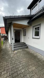 a white house with a porch and a staircase at Shine Apartment Schwarzenfeld in Schwarzenfeld