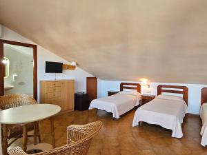 a room with two beds and a table and chairs at Hotel Blue Spot in Malgrat de Mar