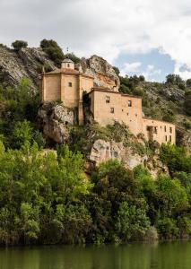 un bâtiment situé sur une colline à côté d'une masse d'eau dans l'établissement Soria Naturaleza, à Soria