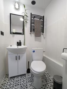 a white bathroom with a toilet and a sink at Kolejowy Zajazd 1 in Łódź
