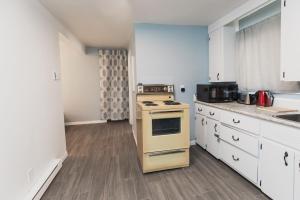 cocina con estufa amarilla y armarios blancos en Avenir Centre Suite en Moncton