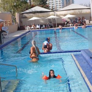 a group of people swimming in a swimming pool at Hotel Apartment okeanos bamarina in Herzliya Pituah