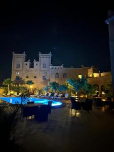 a large building with tables and chairs at night at Kasbah Ait BenHadda in Skoura