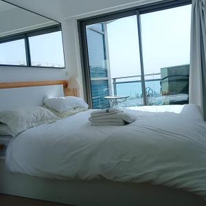 a bedroom with a white bed with a large window at Hotel Apartment okeanos bamarina in Herzliya Pituah