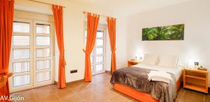 a bedroom with orange curtains and a bed and two windows at El Palacio in Gijón