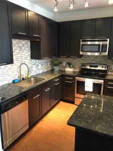 a kitchen with black cabinets and stainless steel appliances at BEAUTIFUL STUDIO 7MIN FROM THE GALLERIA MALL in Houston