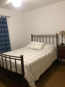 ein Schlafzimmer mit einem Bett mit weißer Bettwäsche und einer Lampe in der Unterkunft AlquilertemporarioGP in General Pico