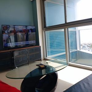 a living room with a glass table and a tv at Hotel Apartment okeanos bamarina in Herzliya Pituah