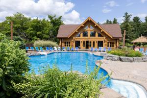 Cabaña de madera con piscina frente a una casa en Chalet Authentik 50 - Hot tub, Pools, Lake & Resort, en Mille-Isles