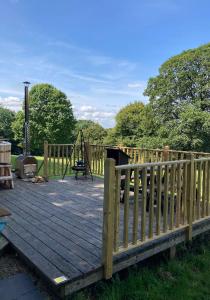 een houten terras met een speeltuin met een houten hek bij Eisa Yurt in York