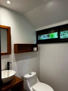 a bathroom with a white toilet and a sink at Hotel Arenal Glamping in Fortuna