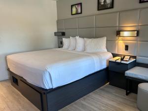 a hotel room with a large bed with white sheets at Signature Inn Santa Clara in Santa Clara