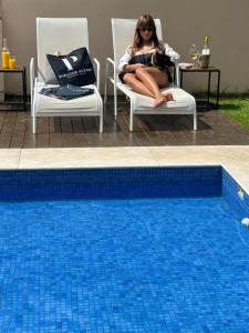 una mujer sentada en una silla junto a una piscina en Parador Búzios Boutique Hotel, en Búzios