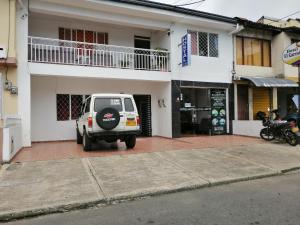 una macchina bianca parcheggiata di fronte a un edificio di Hotel El Carretero a Popayan
